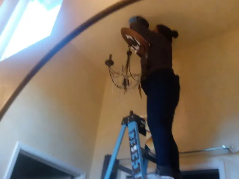 Electrician installing a chandelier in a Laureldale residence